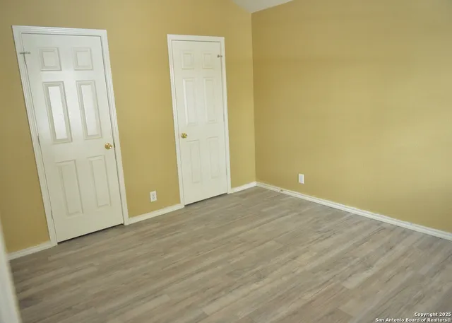 an empty room with wooden floor and closet area
