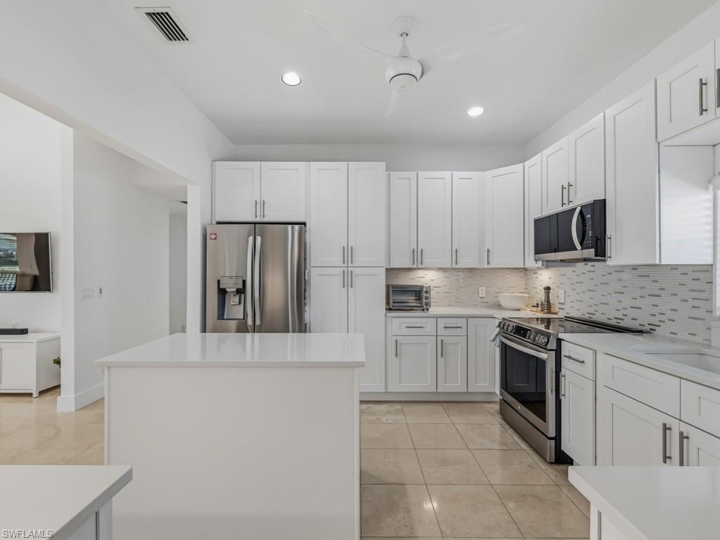 396 Conners Avenue Naples, FL 34108 - Photo 13 of 27 a kitchen with kitchen island a stove a sink and a refrigerator