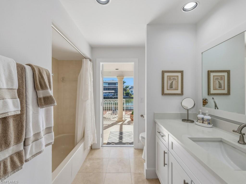396 Conners Avenue Naples, FL 34108 - Photo 22 of 27 a bathroom with a double vanity sink a mirror and a bathtub