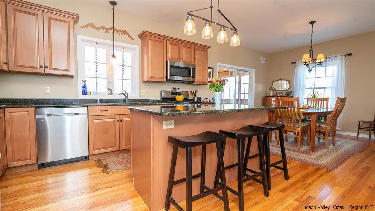 2108 Bruynswick Road Wallkill, NY 12589 - Photo 12 of 34 a kitchen with stainless steel appliances granite countertop a stove top oven a sink a dining table and chairs with wooden floor