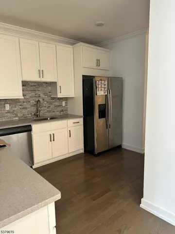 a kitchen with granite countertop white cabinets and refrigerator