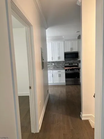 a kitchen with stainless steel appliances a refrigerator a stove top oven and white cabinets