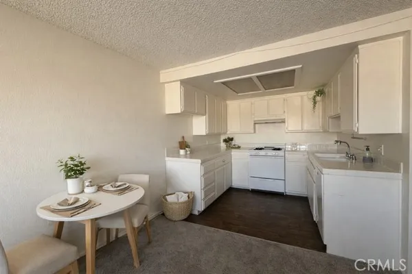 a kitchen with white cabinets a sink dishwasher and a stove with wooden floor