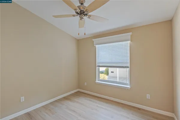 an empty room with a window and a fan