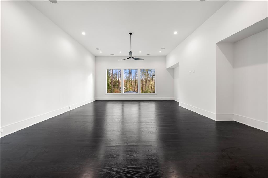 5211 Powers Ferry Road Northwest Sandy Springs, GA 30327 - Photo 84 of 106 an empty room with wooden floor chandelier fan and windows