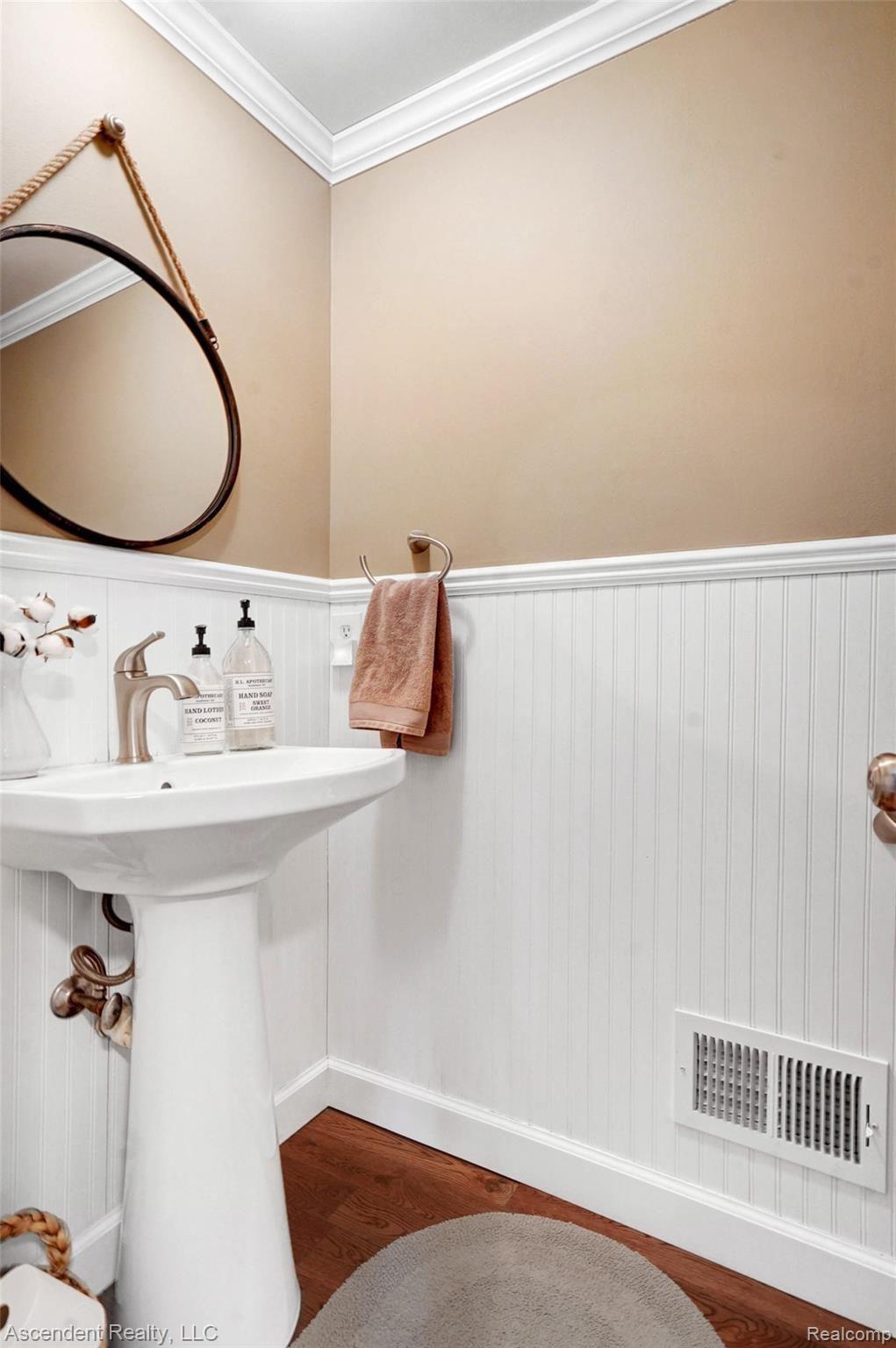 712 Dressler Lane Rochester, MI 48307 - Photo 14 of 30 Powder Room with pedestal lavatory, crown moldings, beadboard wainscoting on walls and hardwood flooring.