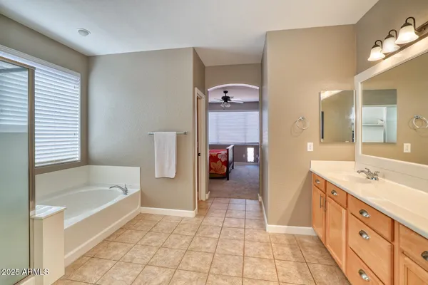 a spacious bathroom with a tub sink and mirror