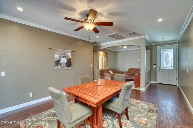 a dining room with wooden floor a chandelier a wooden table and chairs