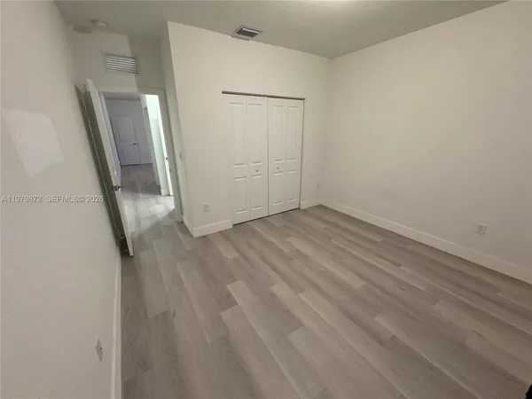 an empty room with wooden floor and mirror