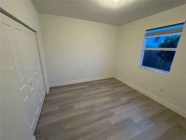 a view of an empty room with wooden floor and hallway