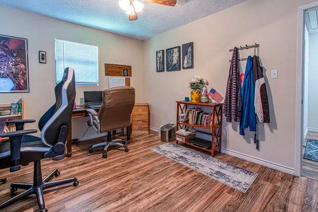 a view of a workspace with wooden floor and furniture