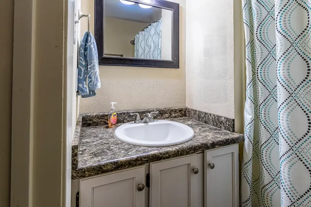 a bathroom with a granite countertop sink and a mirror