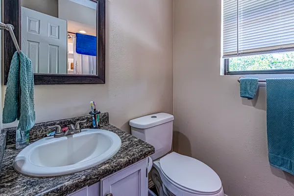 a bathroom with a granite countertop toilet sink and mirror