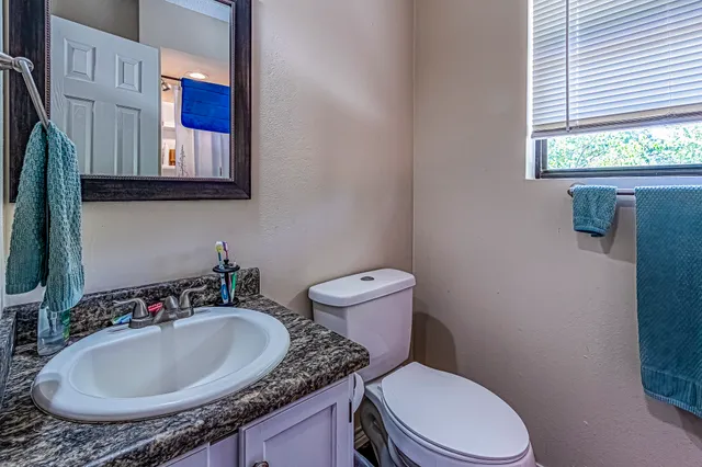 a bathroom with a granite countertop toilet sink and mirror