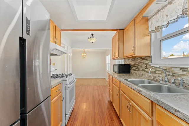 a kitchen with a sink a counter top space wooden floor and stainless steel appliances