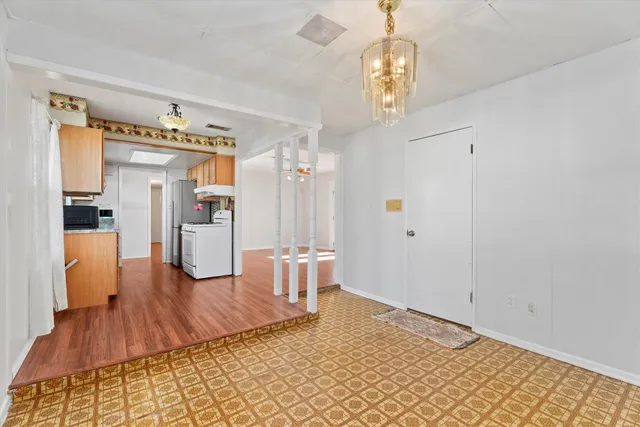 a view of a hallway with wooden floor and a chandelier