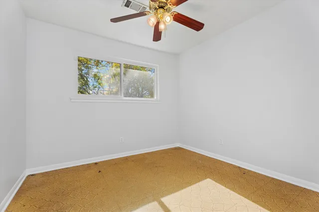 an empty room with ceiling fan and window
