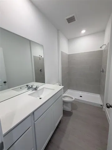 a bathroom with a granite countertop sink a toilet and shower