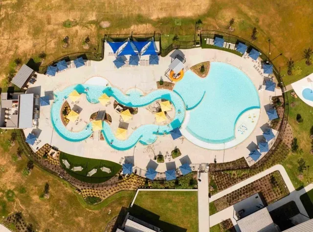an aerial view of a swimming pool with outdoor seating and yard