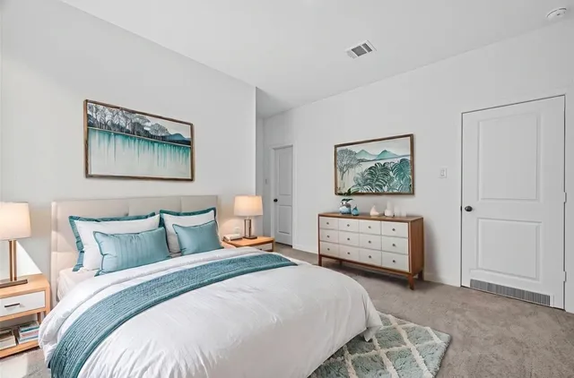 a bedroom with a bed and a lamp on dresser