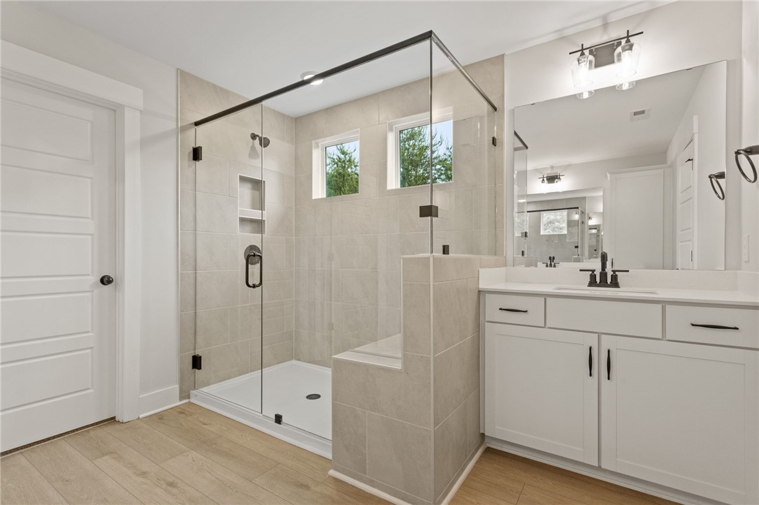 313 Old Shirley Road Central, SC 29630 - Photo 24 of 30 This modern bathroom features a spacious glass-enclosed shower, elegant vanity, and light wood flooring.