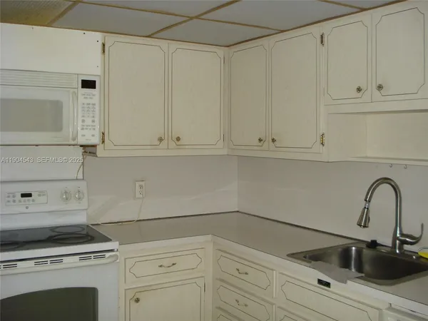 a kitchen with white cabinets and white appliances