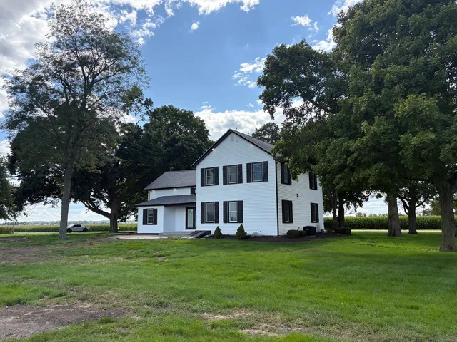 a view of a white house with a big yard and large trees