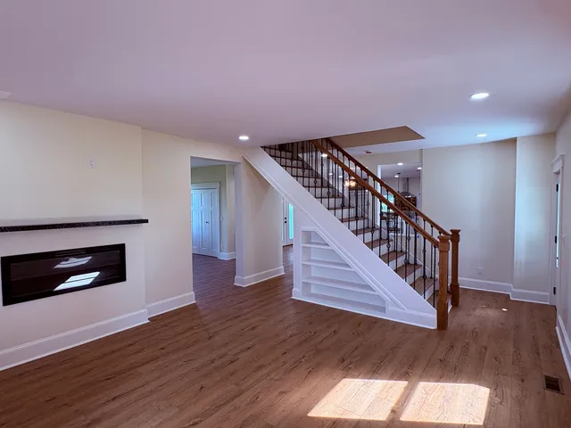 a view of an empty room with wooden floor fireplace and a window