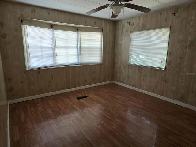 a view of an empty room with a window and wooden floor