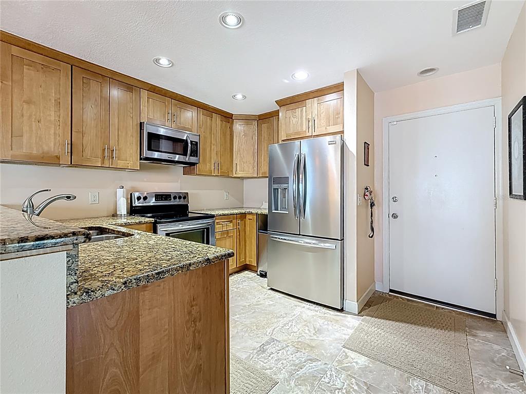 230 Medallion Boulevard, Unit G Madeira Beach, FL 33708 - Photo 10 of 38 a kitchen with a refrigerator a microwave a sink and cabinets