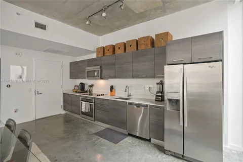 a kitchen with stainless steel appliances granite countertop a refrigerator a sink and white cabinets