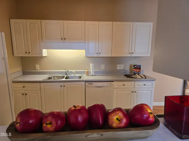 a kitchen with white cabinets and sink
