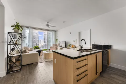 a view of a kitchen counter space a sink wooden floor and windows