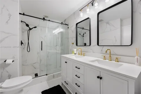 a bathroom with a double vanity sink toilet mirror and shower
