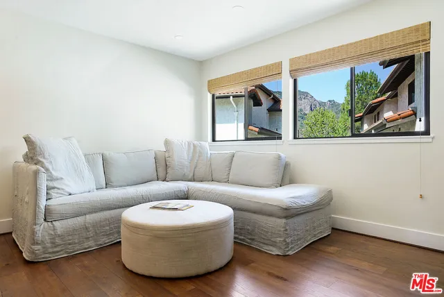 a living room with furniture kitchen view and a wooden floor
