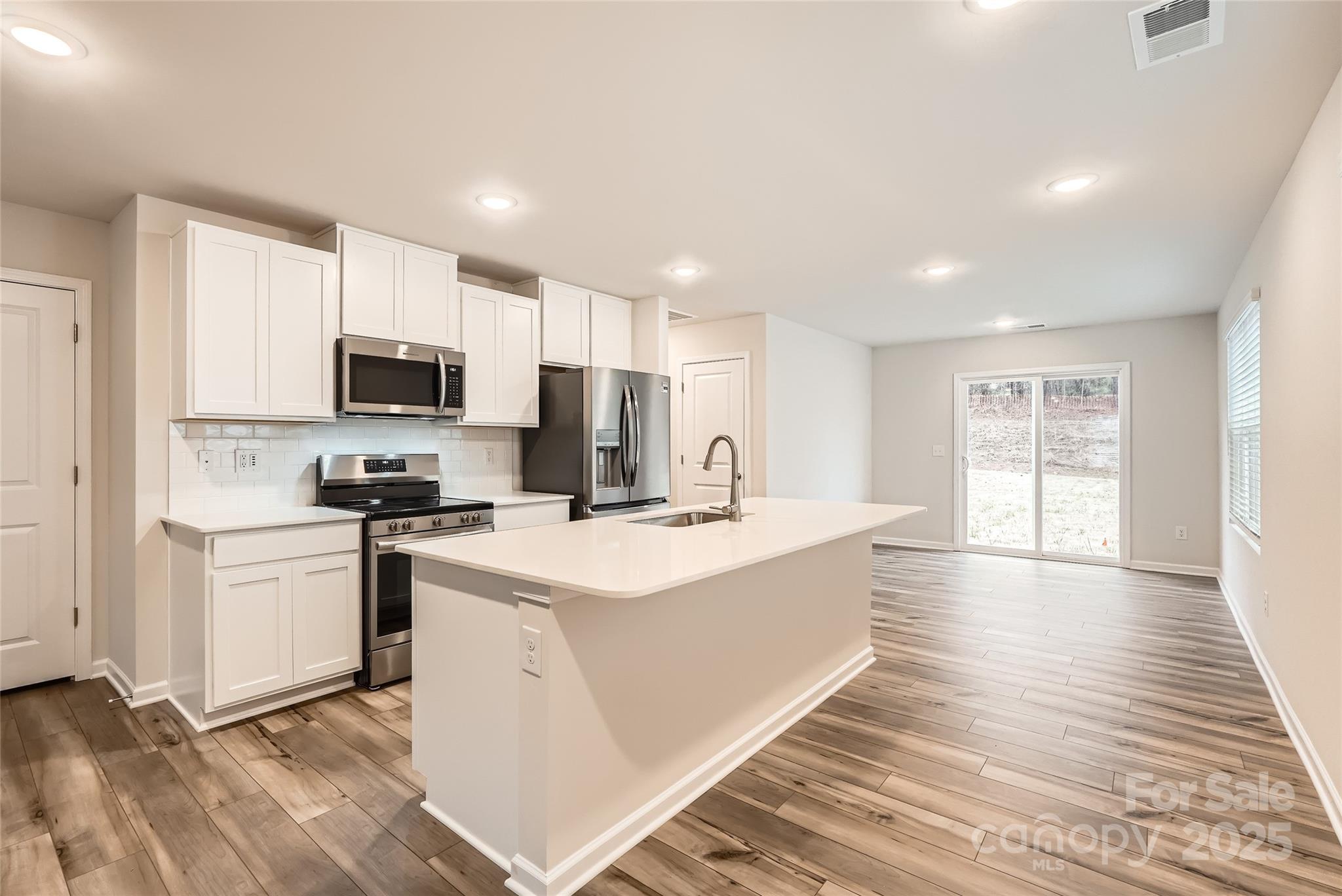 1608 Cannonball Lane Bessemer City, NC 28016 - Photo 5 of 13 a large white kitchen with wooden floor and a sink