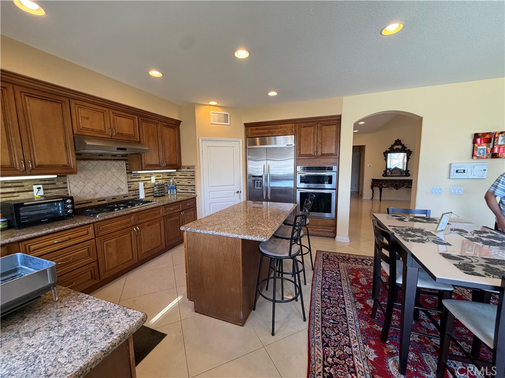 19823 Mariposa Pines Way Porter Ranch, CA 91326 - Photo 12 of 50 a kitchen with stainless steel appliances granite countertop a stove top oven a sink dishwasher and cabinets with wooden floor