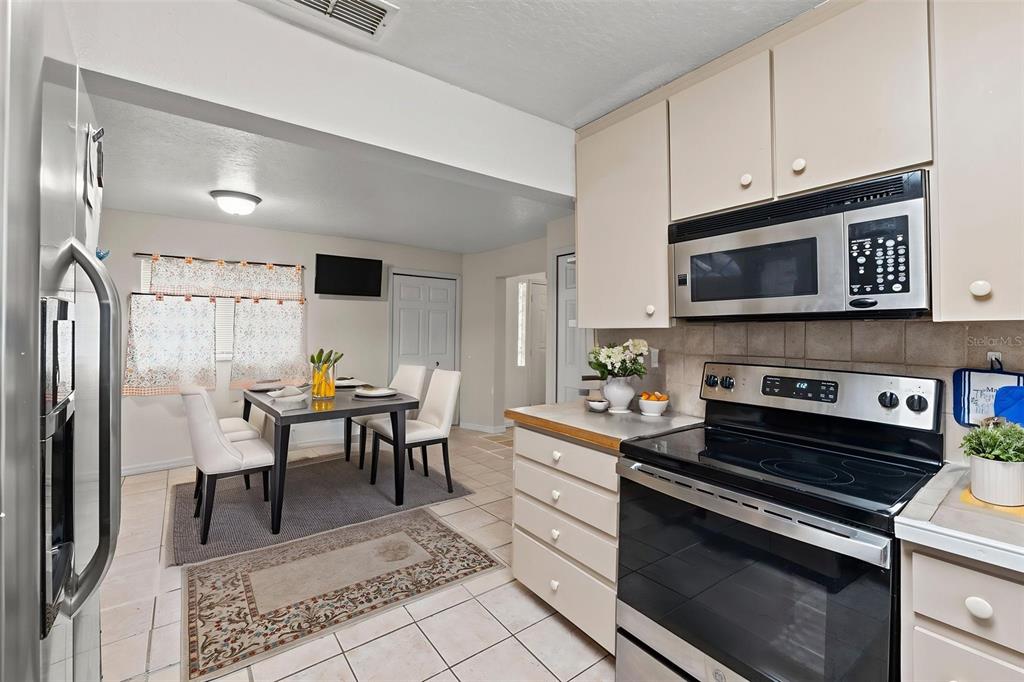 304 Shepard Avenue Dundee, FL 33838 - Photo 36 of 62 a kitchen with stainless steel appliances kitchen island granite countertop a stove a sink and a microwave