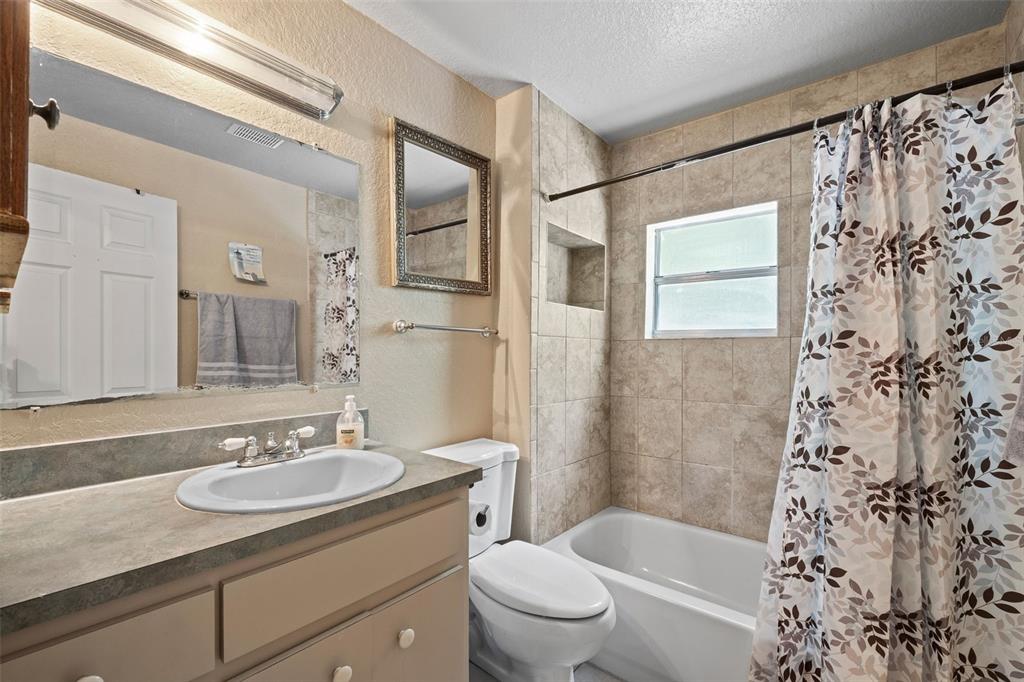 304 Shepard Avenue Dundee, FL 33838 - Photo 41 of 62 a bathroom with a granite countertop sink toilet a mirror a bathtub and shower