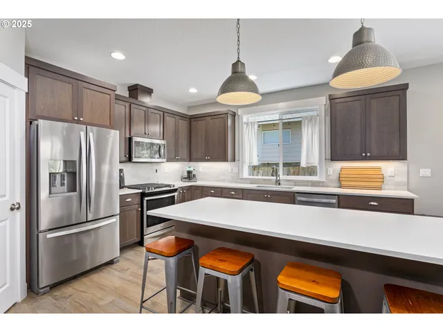 a kitchen with stainless steel appliances granite countertop a sink a stove and refrigerator