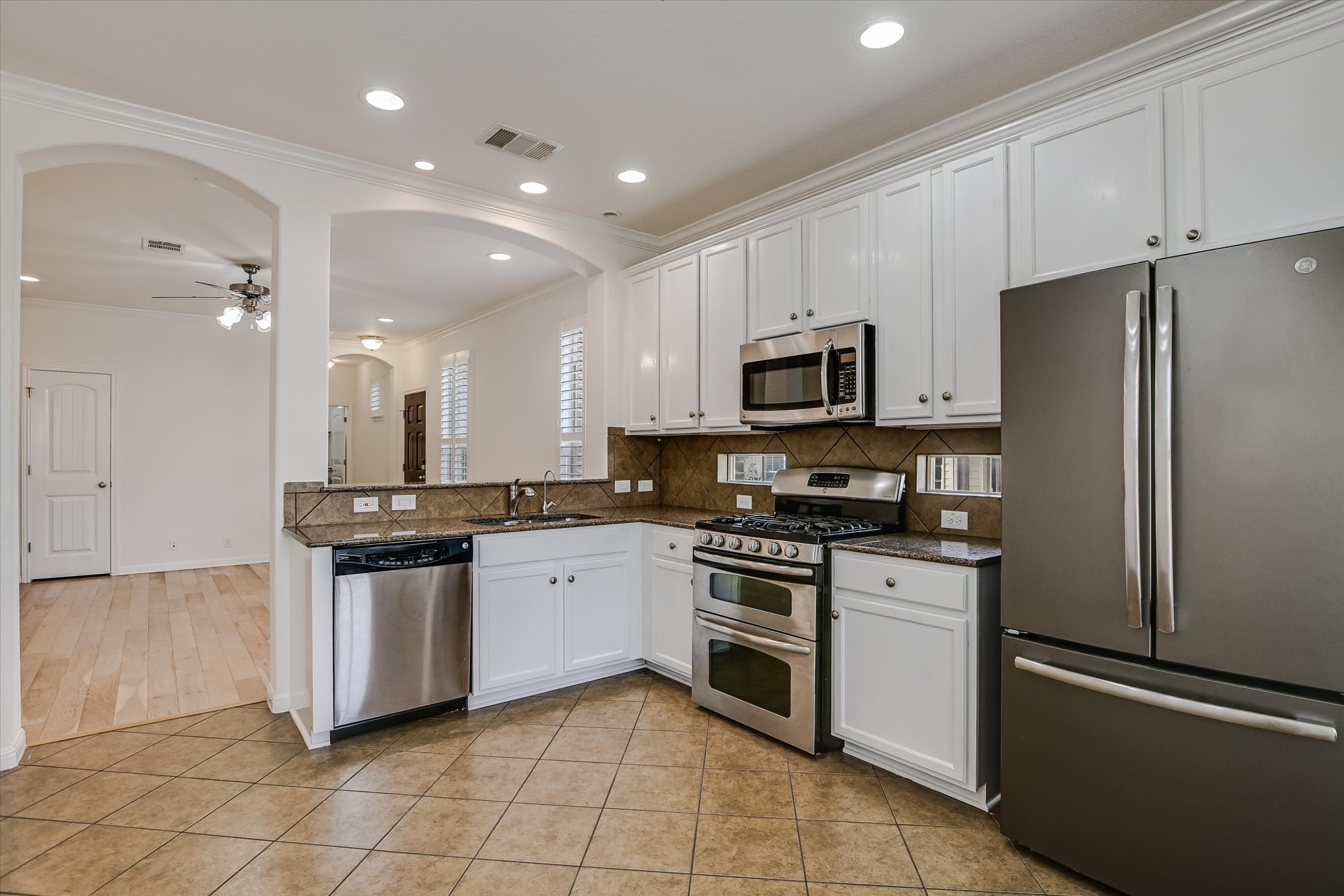 14001 Avery Ranch Boulevard, Unit 1601 Austin, TX 78717 - Photo 5 of 25 Kitchen featuring stainless steel appliances, white cabinets, ornamental molding, light tile patterned flooring, and tasteful backsplash- All Appliances Convey