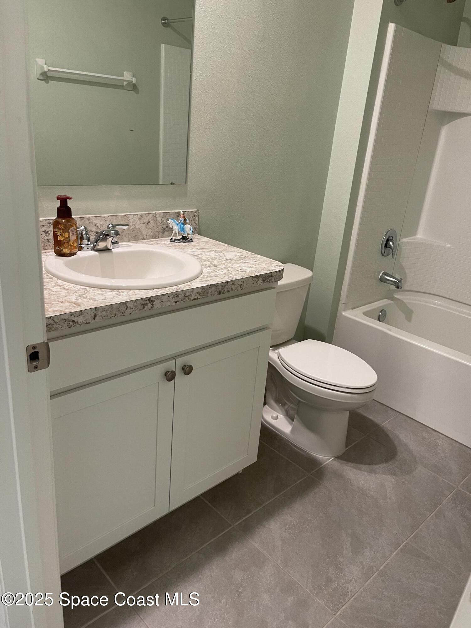 7055 Topaz Drive Grant-Valkaria, FL 32949 - Photo 8 of 24 a bathroom with a granite countertop sink a toilet and a large mirror
