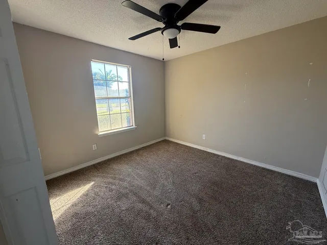 an empty room with windows and fan