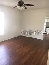 an empty room with wooden floor and ceiling fan
