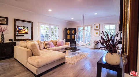 a living room with furniture a large window and wooden floor