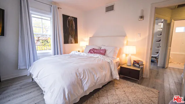 a spacious bedroom with a bed and wooden floor
