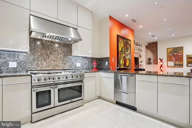a kitchen with stainless steel appliances granite countertop a stove and white cabinets
