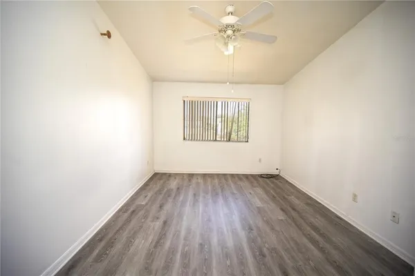 an empty room with a hardwood and ceiling fan