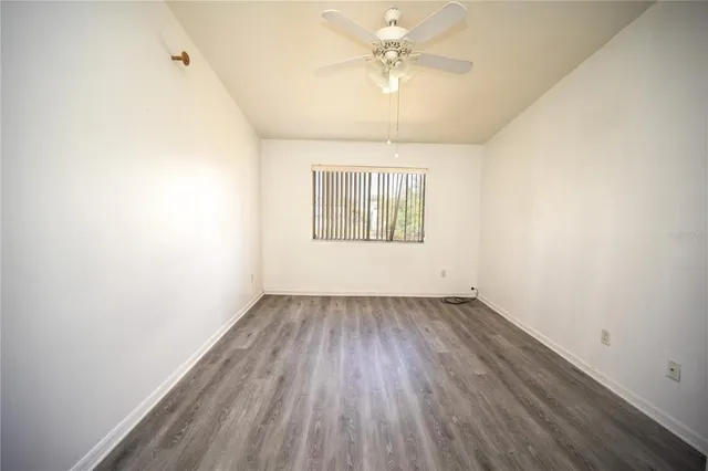 an empty room with a hardwood and ceiling fan