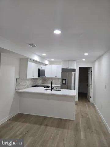 a large white kitchen with kitchen island a sink stainless steel appliances and cabinets